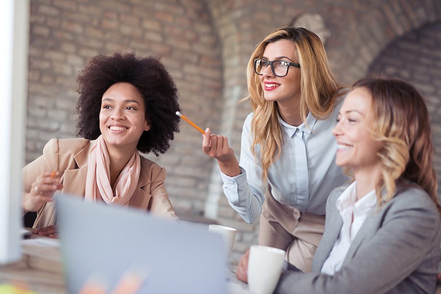 Business Insurance - Group of Young Woman Working Together During a Meeting In Their Office With a Brick Wall Background